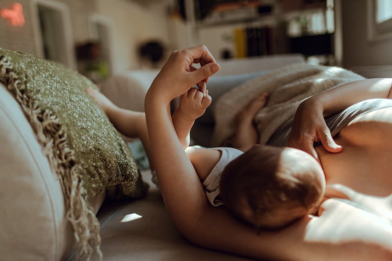 Mother breastfeeding her baby at home on the sofa